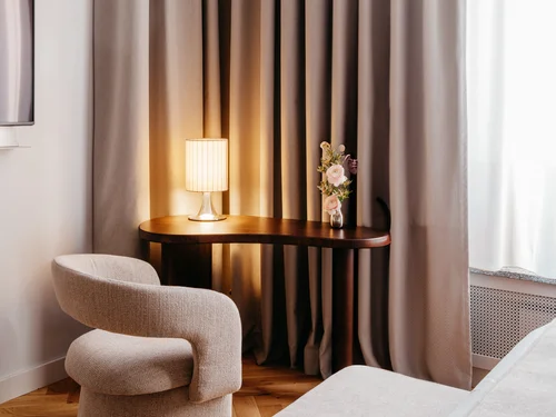Ihr Stadthotel in Berlin: DASEYN | Fischerinsel Gemütlicher Sitzbereich mit Tischlampe, Blumen und Vorhängen in warmem Licht