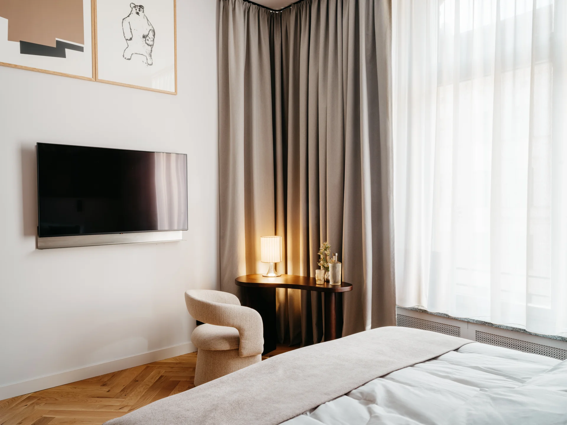 Ihr Stadthotel in Berlin: DASEYN | Fischerinsel Modernes Hotelzimmer mit Fernseher, gemütlichem Stuhl und Vorhängen